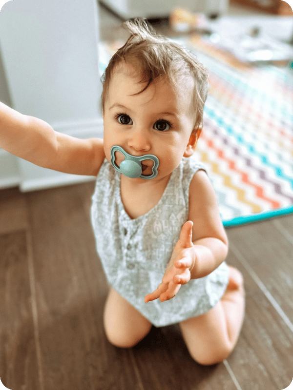 Infant looks at the camera with a pacifier in their mouth.