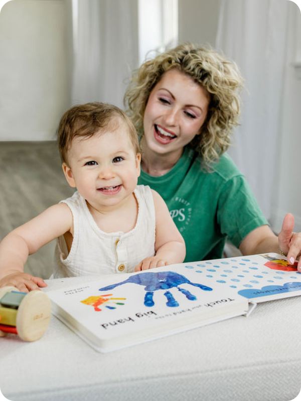 Baby and mom smile while looking at a book together