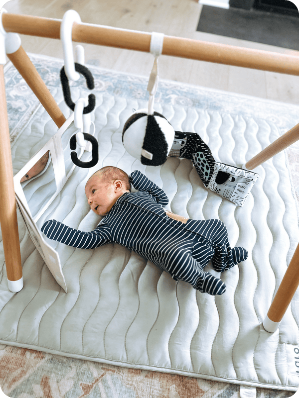 Newborn baby plays on an activity mat