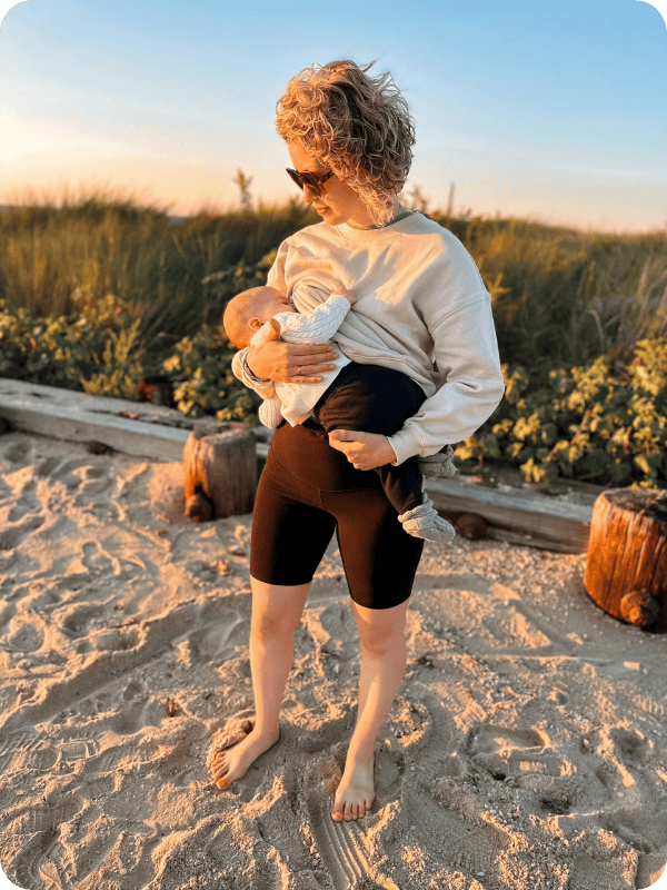 Mom holds baby while breastfeeding on the beach