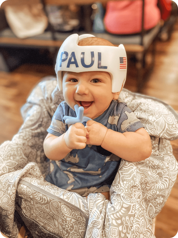 ~6 month old infant holds a teether up to his mouth