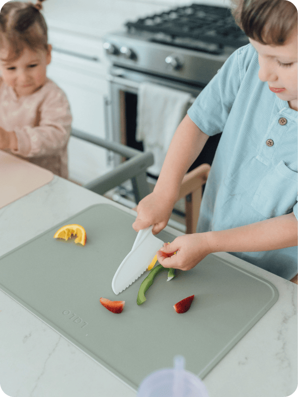 Toddler uses child-safe knife to chop vegetables