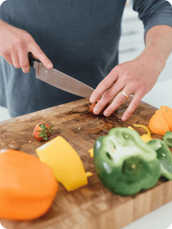 Man chops vegetables and fruit on a wooden cutting board