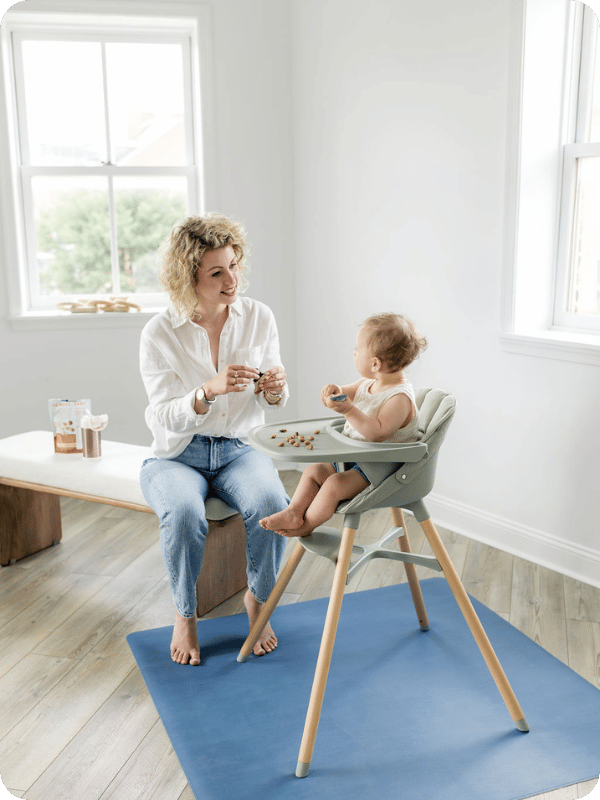 Mom feeds baby a snack in the high chair