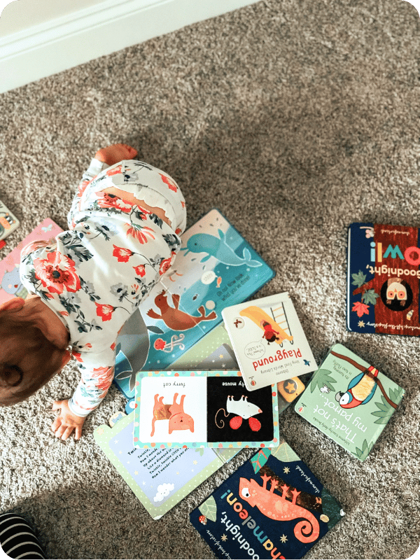 Infant crawls by a pile of picture books