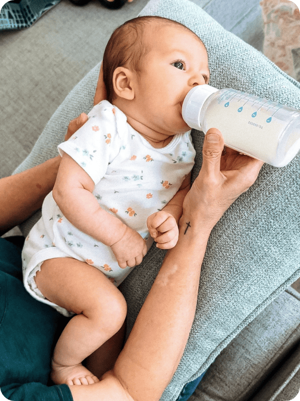 Dad holds baby in the elevated side lying position to take a bottle
