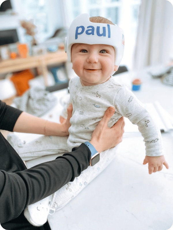Paul smiles at the camera, showing off his white cranial helmet. His name is on the front of the helmet in blue letters