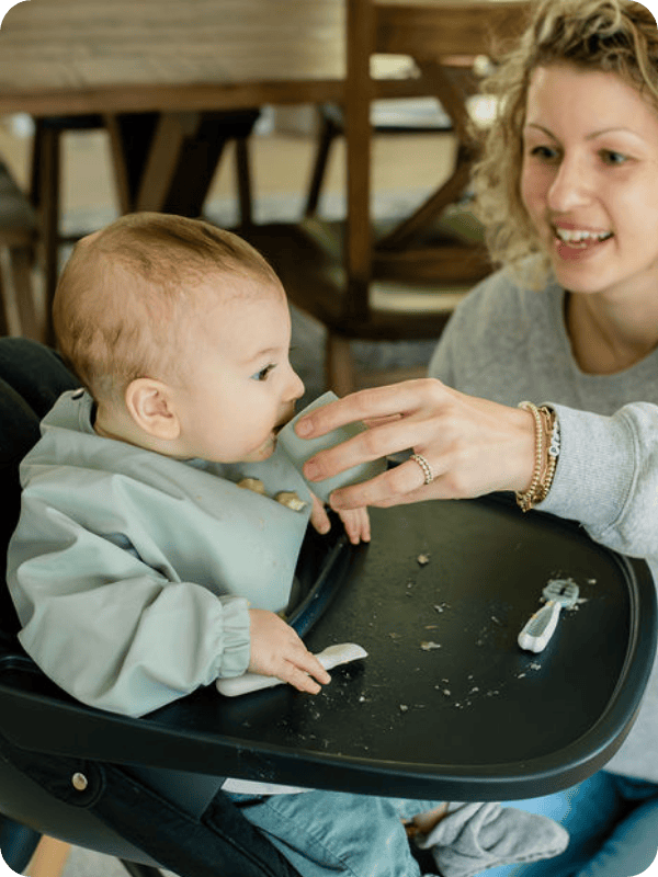 Mom gives her infant a sip of liquid from an open cup