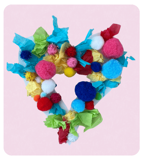Pom pom heart wreath craft for toddlers on a pink background.