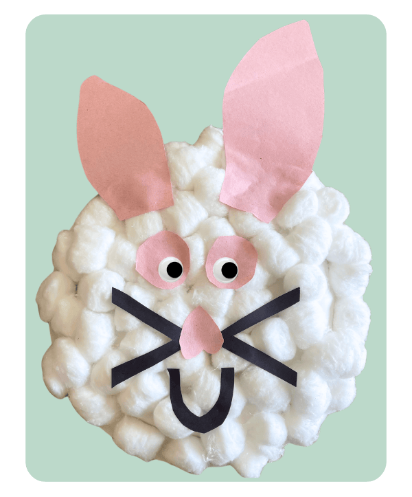 Cotton ball bunny craft for toddlers on a green background.