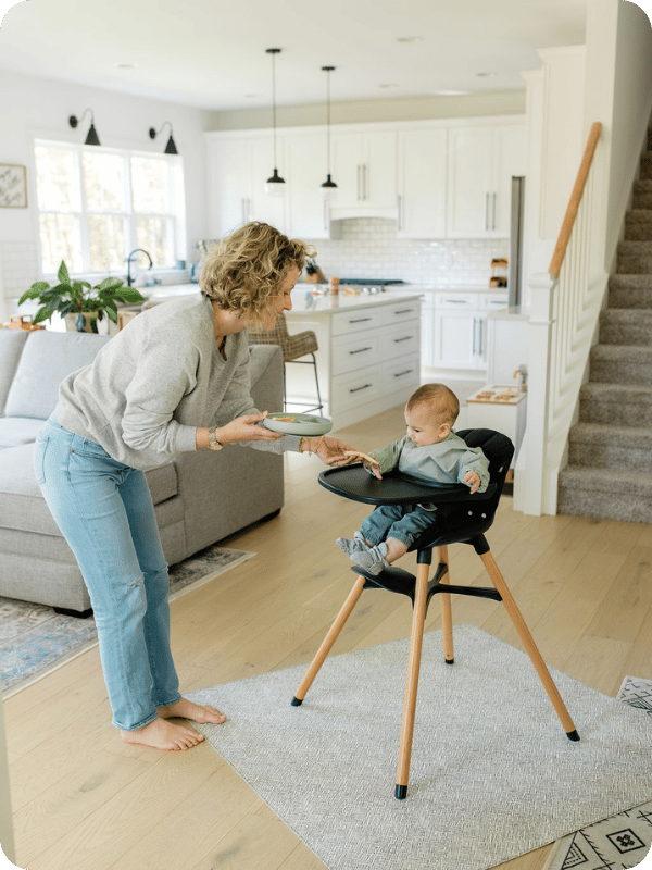 Mom places food on the high chair tray for baby
