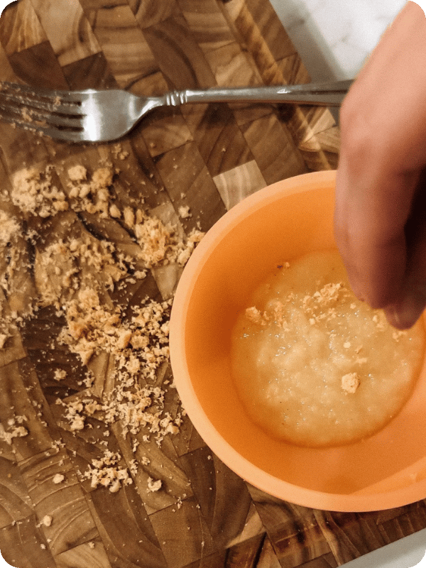 Crumbs being sprinkled over a puree food to help thicken it.