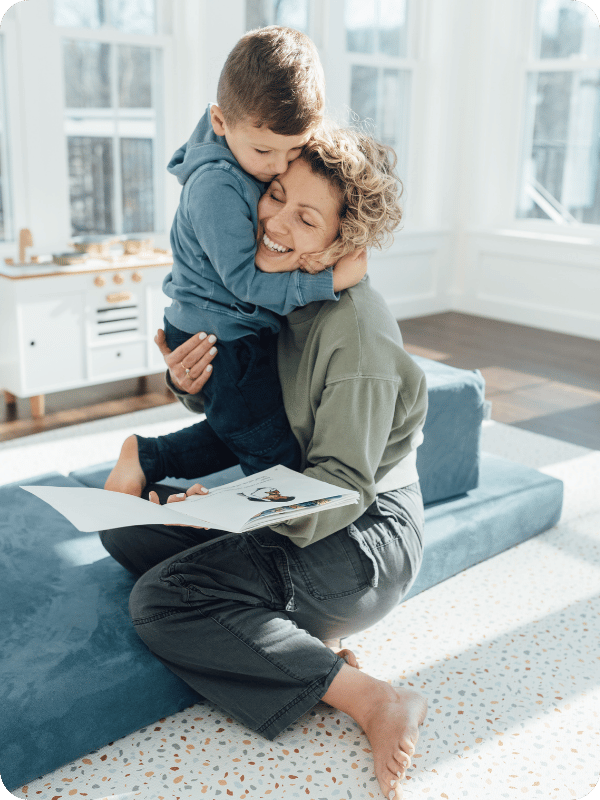 toddler hugs mom while they play and read books together