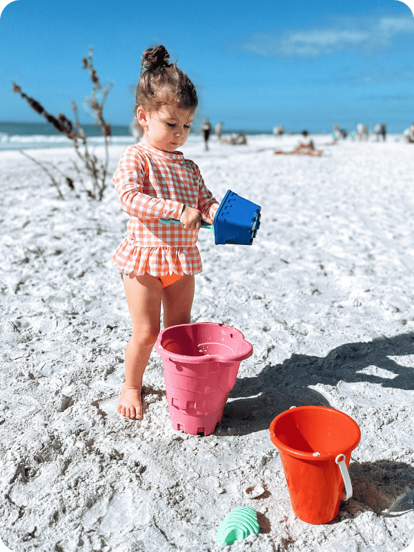 toddler girl wearing rufflebutts toddler swimsuit at the beach
