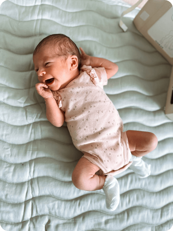 Newborn lays on an activity mat for floor play.