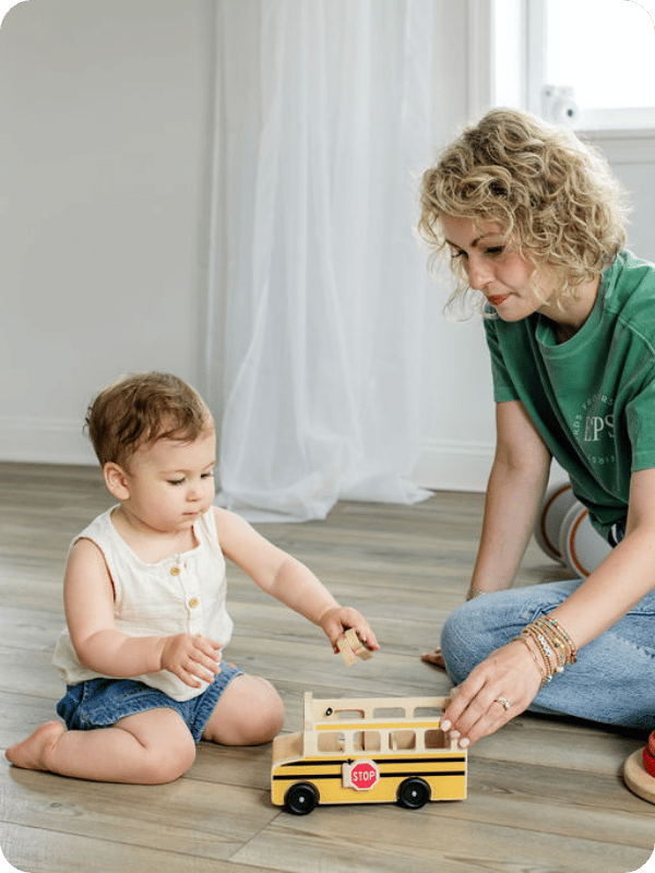 Mom and baby play with a wooden toy together while baby sits in the W position