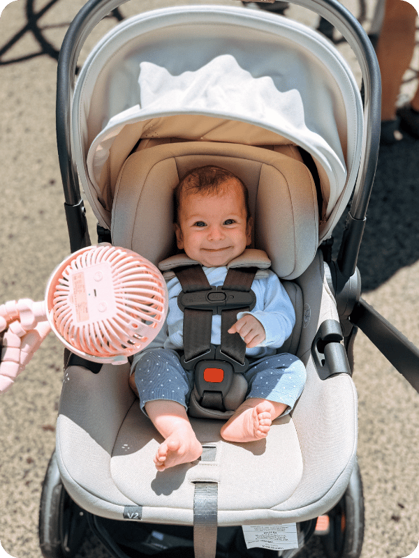 infant riding in a stroller with a stroller fan