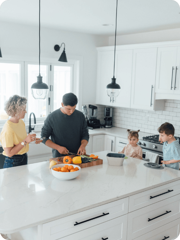 Mom and dad chop vegetables for their toddlers at the kitchen island