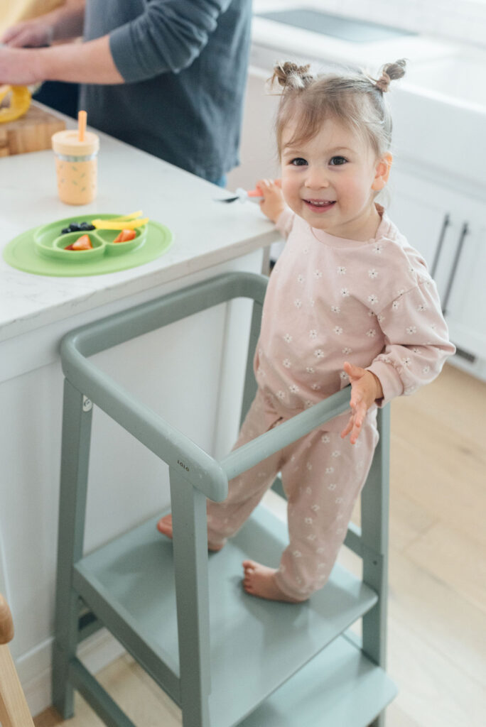 toddler girl in Lalo toddler tower eating a snack at the counter