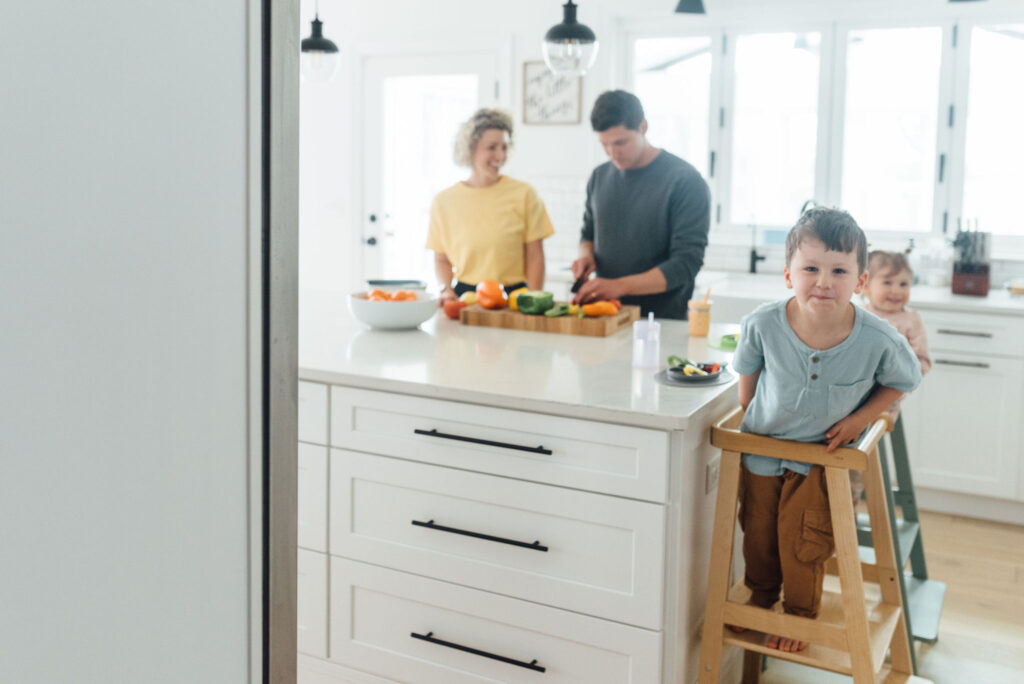 toddler boy and toddler girl on Lalo's The Tower (learning tower) eating a snack at the island in the kitchen