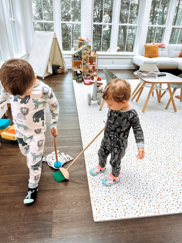 Two toddlers playing with a pretend play cleaning se