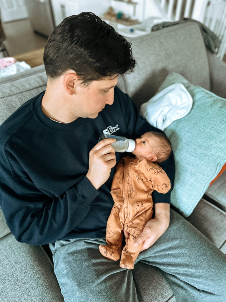 Father feeds baby a bottle of breastmilk.