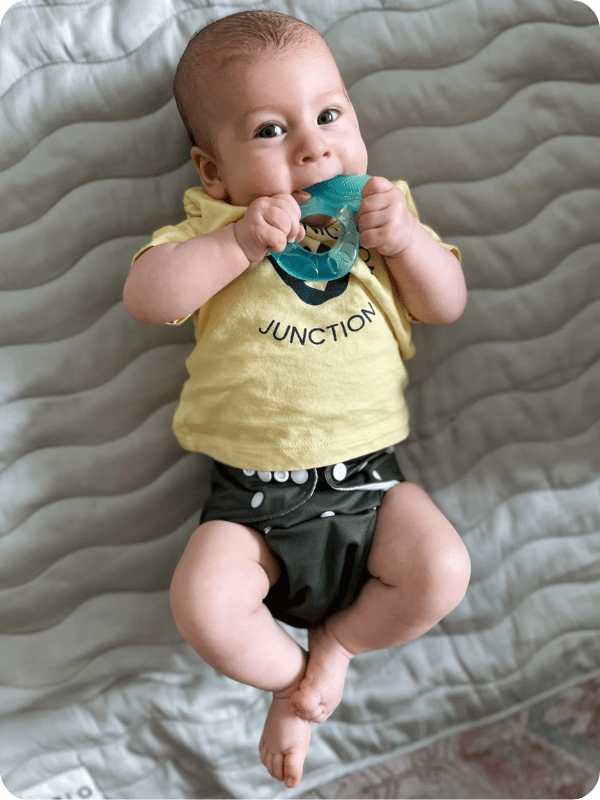 Infant holds teether to their mouth