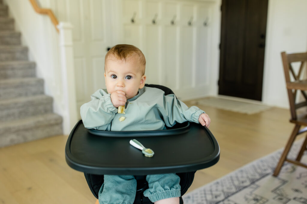 Baby eating from a spoon in the high chair