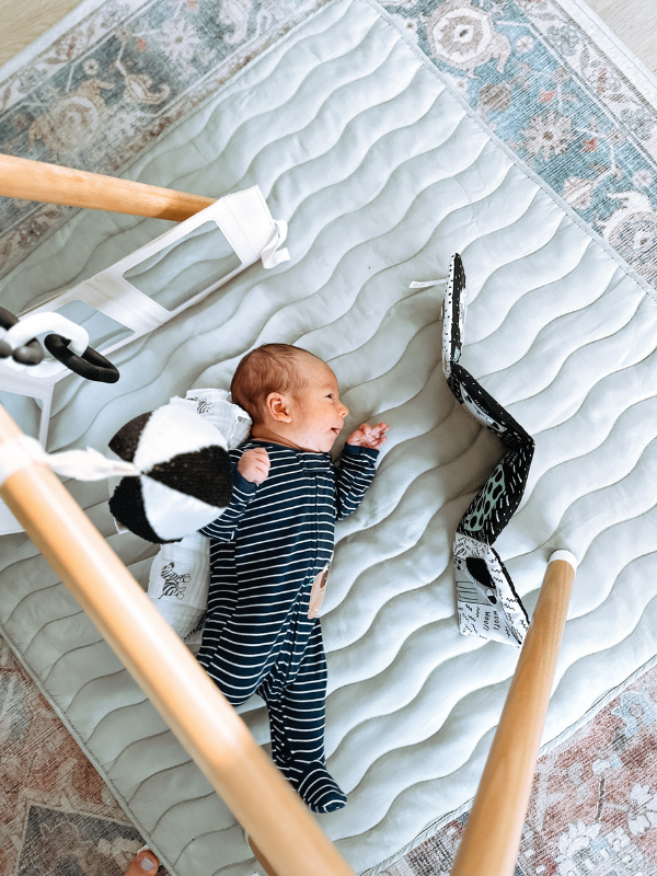 Baby playing on side on floor.