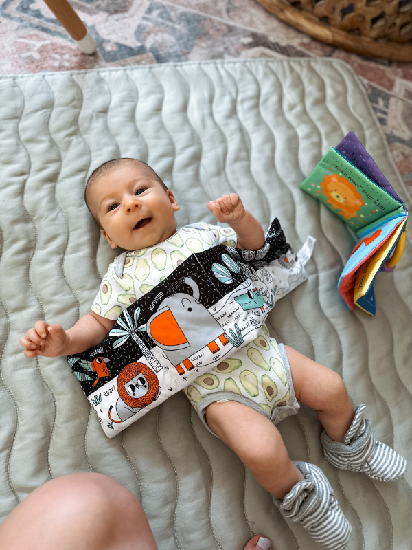 Two month old baby plays in play gym
