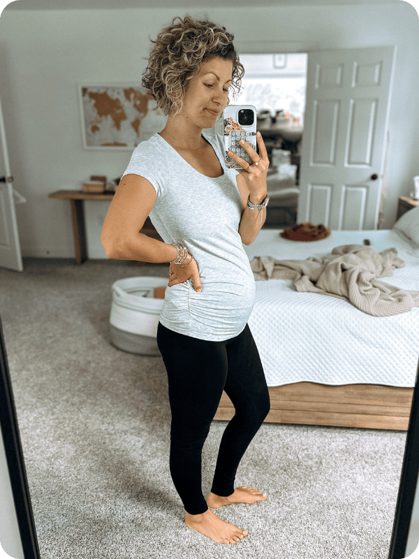 Pregnant woman wearing black Motherhood Maternity leggings styled with a ruched t-shirt