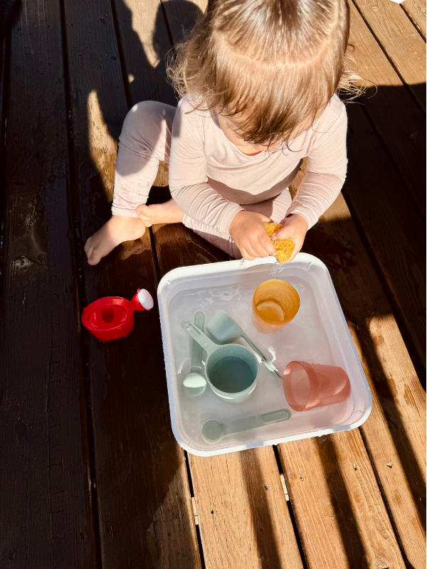 toddler plays in water sensory bin