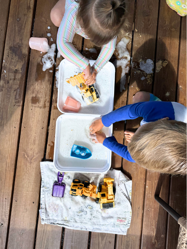 boy and girl playing in sensory bin outside.