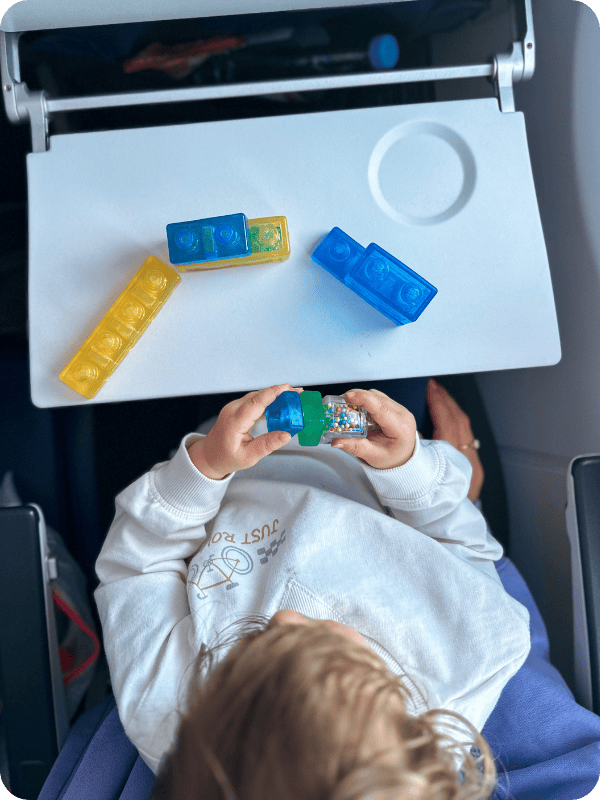 toddler playing with jelly blox on a plane tray table