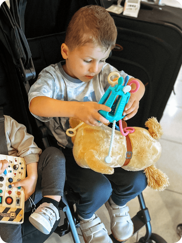 toddler in a stroller playing with Zippee travel toy