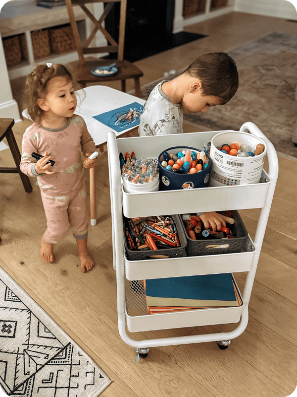 2 toddlers grabbing art supplies to color with 