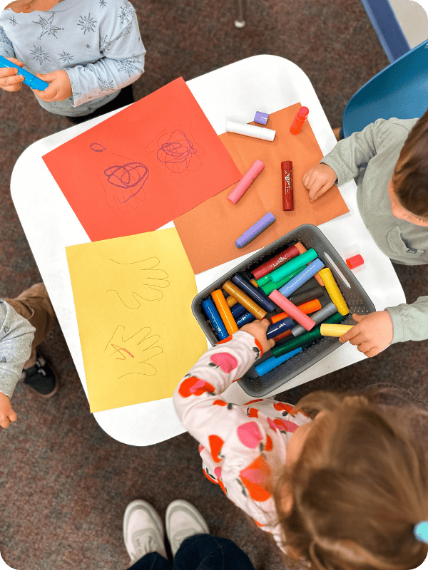 toddlers coloring with paint sticks at a kids' table