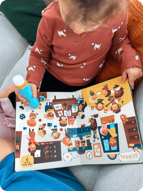 toddler girl playing with the Tappi, using Play Pen to tap the board book