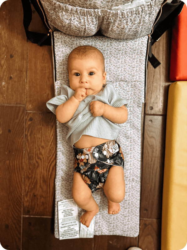 baby laying on Petunia Pickle Bottom diaper bag's fold out changing pad