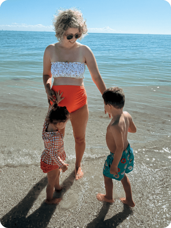 mom with summer mae high waisted maternity swimsuit on with 2 toddlers at the ocean