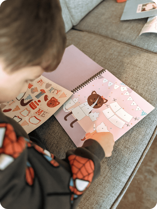 Toddler completes sticker book on couch.