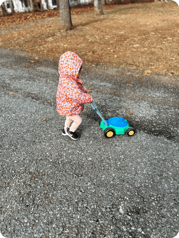18 month old plays with a push toy outside