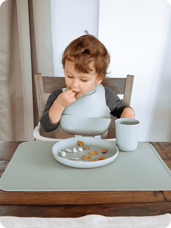 toddler eating in Lalo booster seat at the table