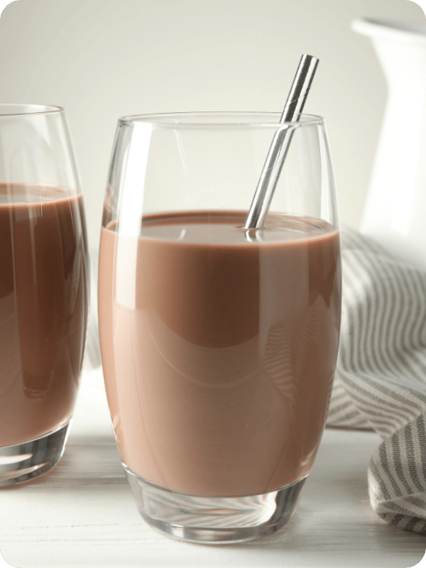A clear glass of chocolate milk with a stainless steel straw