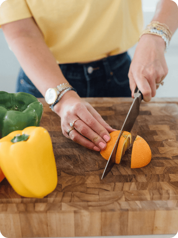 Woman slices an orange on a butcher block