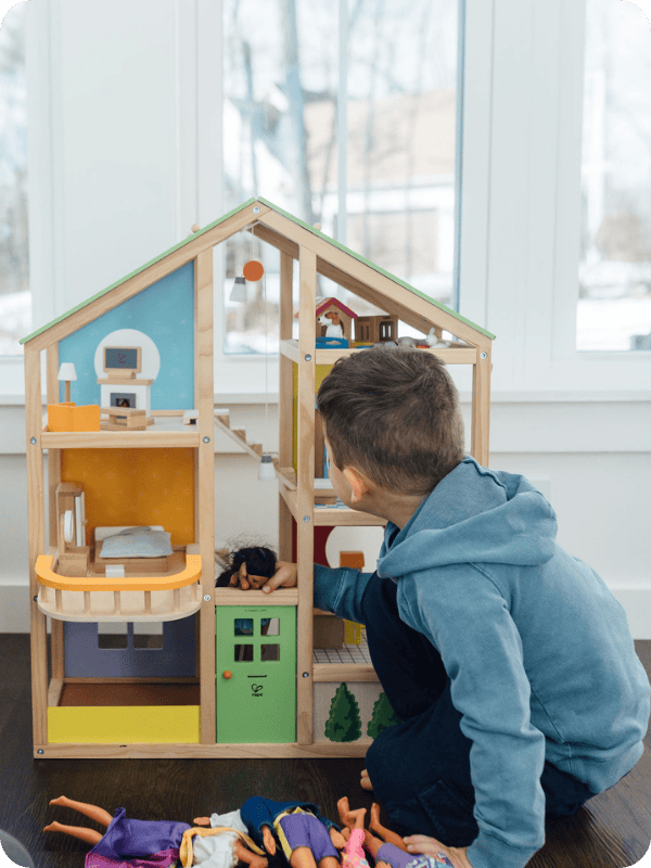 Toddler plays with a wooden dollhouse.
