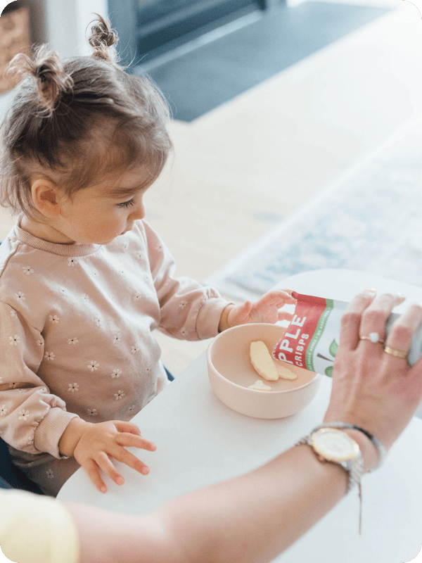 Mom pours a snack into a bowl for a toddler