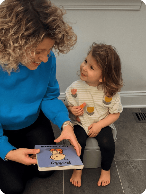 photo of mom reading potty training book to a toddler on the potty chair