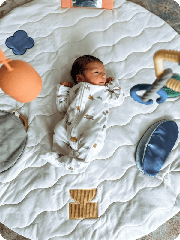 newborn laying on play mat 