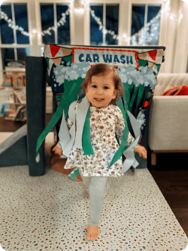 toddler girl playing with play couch car wash panel